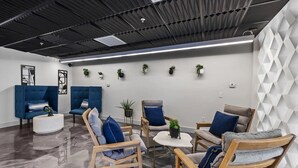 A modern lounge area with blue sofas, wooden chairs, and a white coffee table.