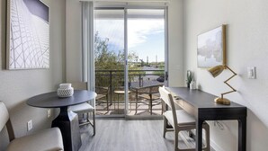 A modern balcony with a dining area, including a table, chairs, and a potted plant.