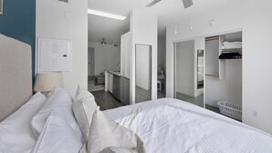 Una habitación de hotel moderna con una cama grande, un baño con espejo y un vestidor.