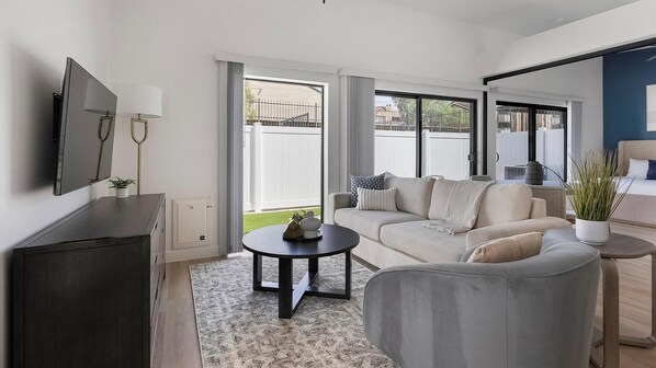 A modern living room with a sofa, a coffee table, and a TV mounted on the wall. - Landing | Incredible 1BD, Gym, Game Room (Phoenix)