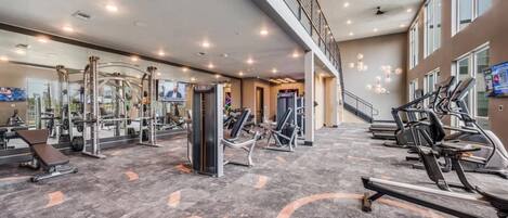 A gym with various exercise equipment, a mirrored wall, and a staircase leading to an upper level.