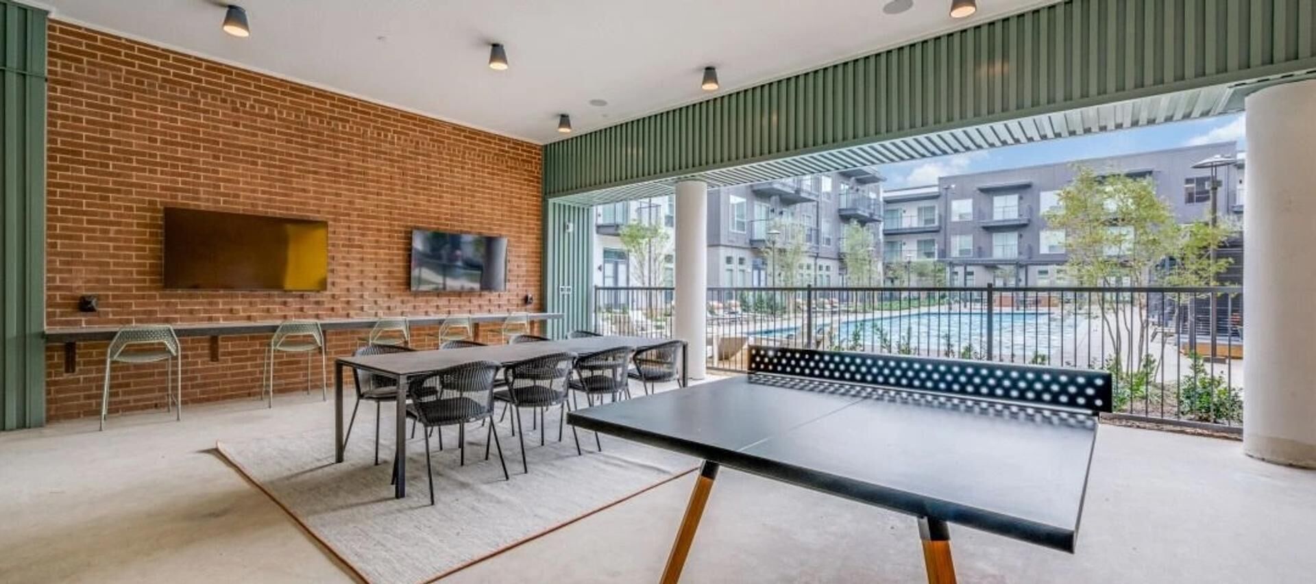 A modern indoor space with a brick wall, a long table with chairs, and a bench.