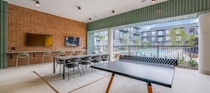 A modern indoor space with a brick wall, a long table with chairs, and a bench. - Landing | Chic 2BD, Courtyard, Pool (Denton)