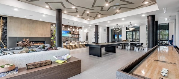 A modern living room with a pool table, a fireplace, and a bar area.