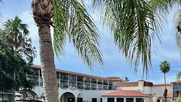 Ein Hotel am Wasser mit einer Anlegestelle, Palmen und einem Gebäude mit Balkonen.