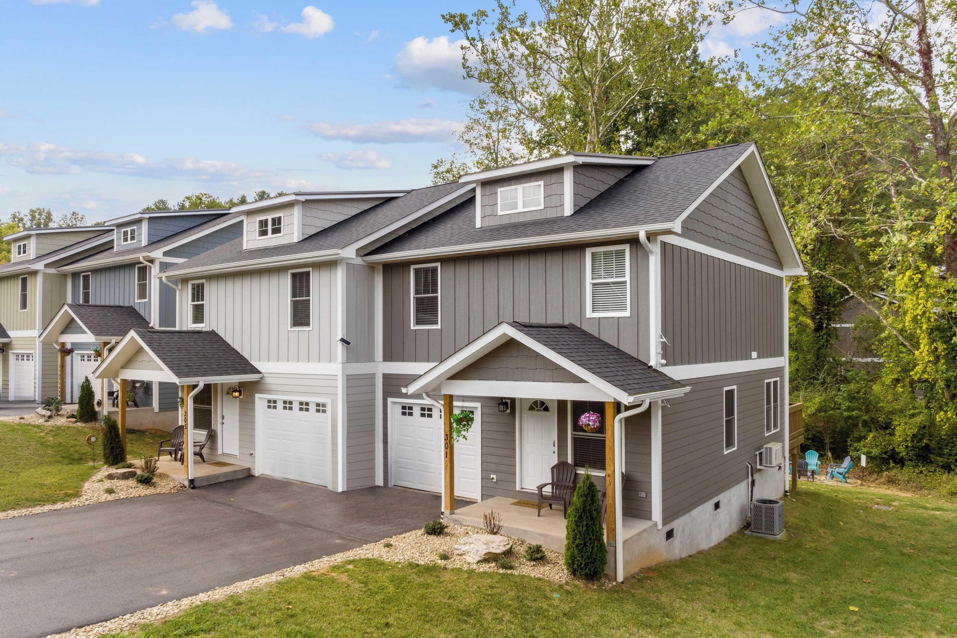 A row of townhouses with attached garages, a covered front porch, and a well-maintained lawn.
