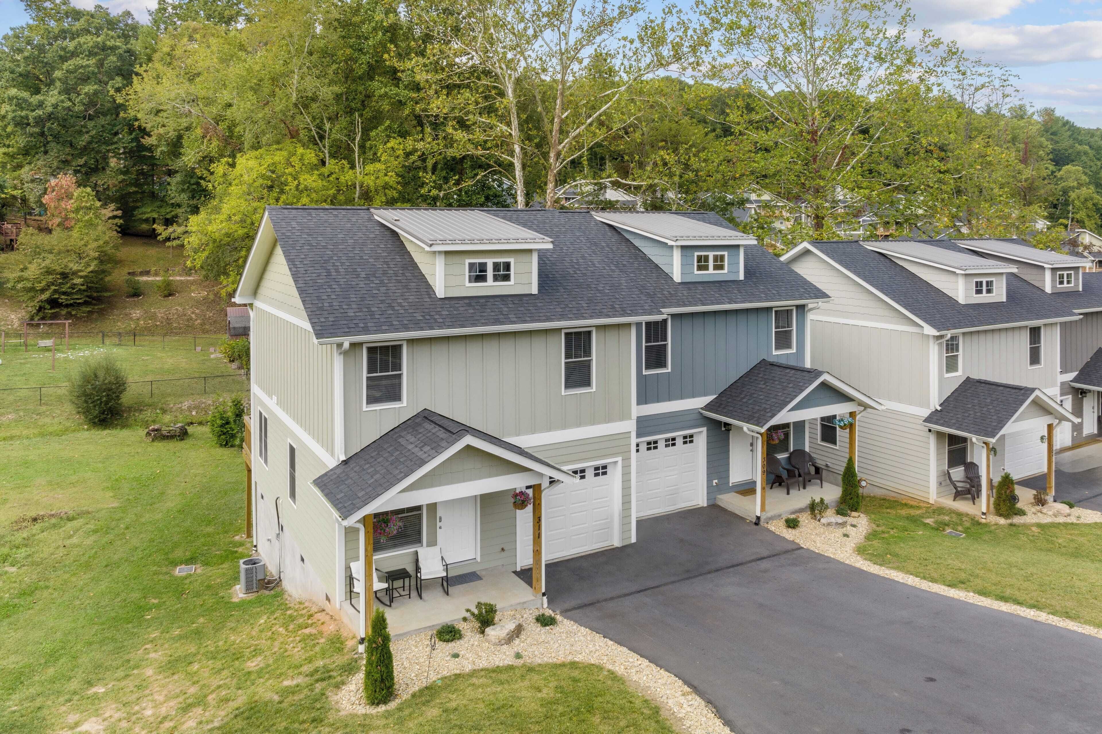 A row of two-story houses with attached garages, a front porch, and a well-maintained lawn.