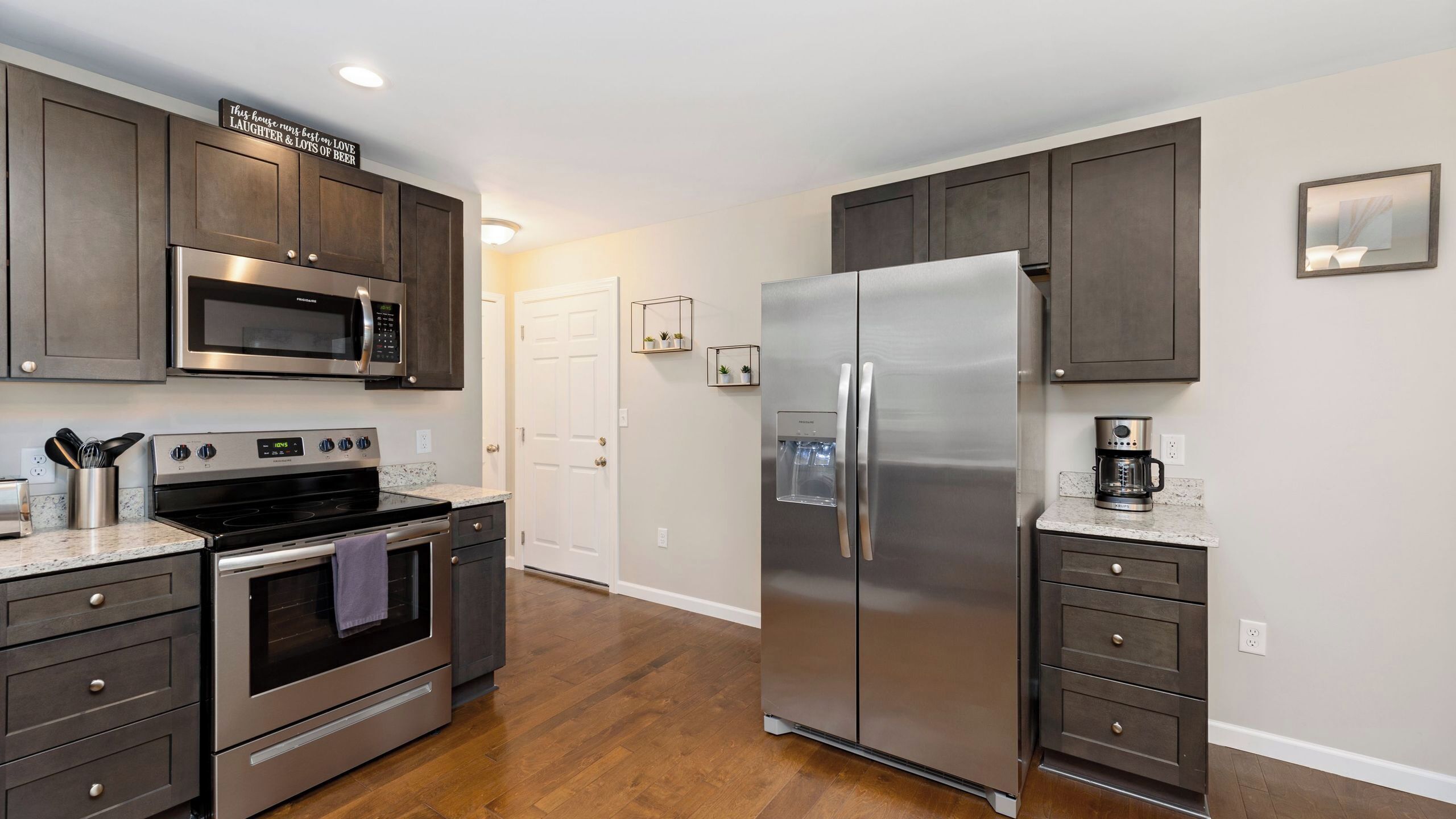 A modern kitchen with stainless steel appliances, wooden cabinets, and a granite countertop.