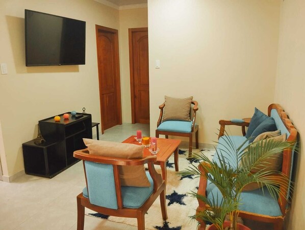 A living room with a sofa, two chairs, a coffee table, and a TV mounted on the wall. - Katari Apart (Piñas)
