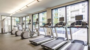 Un gimnasio con cintas de correr, elípticas y bicicletas estáticas.