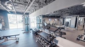 A gym with various exercise equipment, including dumbbells, a bench, and cardio machines.