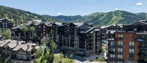 Un resort con edificios de varios pisos, un camino sinuoso y montañas al fondo.