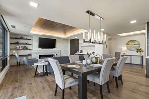A modern dining area with a wooden table, grey upholstered chairs, and a central fireplace. - Abode at Horizon View, ski-in/ski-out, hot tub, panoramic views (Park City)