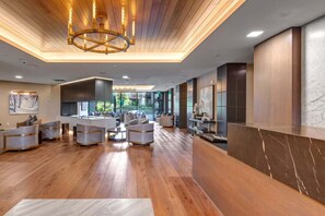 A modern lobby with a wooden floor, a reception desk, and a large chandelier.