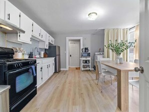A modern kitchen with a stove, oven, microwave, and a dining area with a table and chairs.