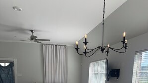 A modern living room with a white sofa, a dining table with four chairs, a ceiling fan, and a chandelier. - Charming 3-bedroom house with AC in Prairieville (Prairieville)
