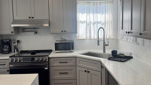 A kitchen with white cabinets, a stove, a microwave, and a sink. - Charming 3-bedroom house with AC in Prairieville (Prairieville)
