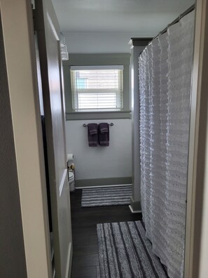 A narrow bathroom with a window, a towel rack, and a striped rug. - Charming 1920s 2-bedroom house in Central Tacoma (Tacoma)