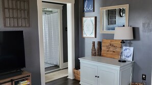 Una sala de estar moderna con un televisor de pantalla plana, un mueble blanco y una mesa de centro con controles remotos.