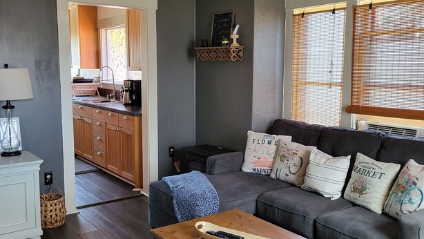 Una sala de estar moderna con un sofá gris, una mesa de centro de madera y un ventilador de techo.
