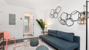 A modern living room with a grey sofa, a pink chair, a patterned rug, and a wall art piece. - Cypress Sycamore by Avantstay 6 Mins to Downtown (Asheville)
