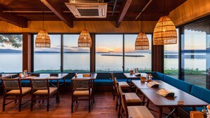 A restaurant with wooden furniture, large windows, and hanging wicker lamps. - ISHINOYA Beppu (Beppu)