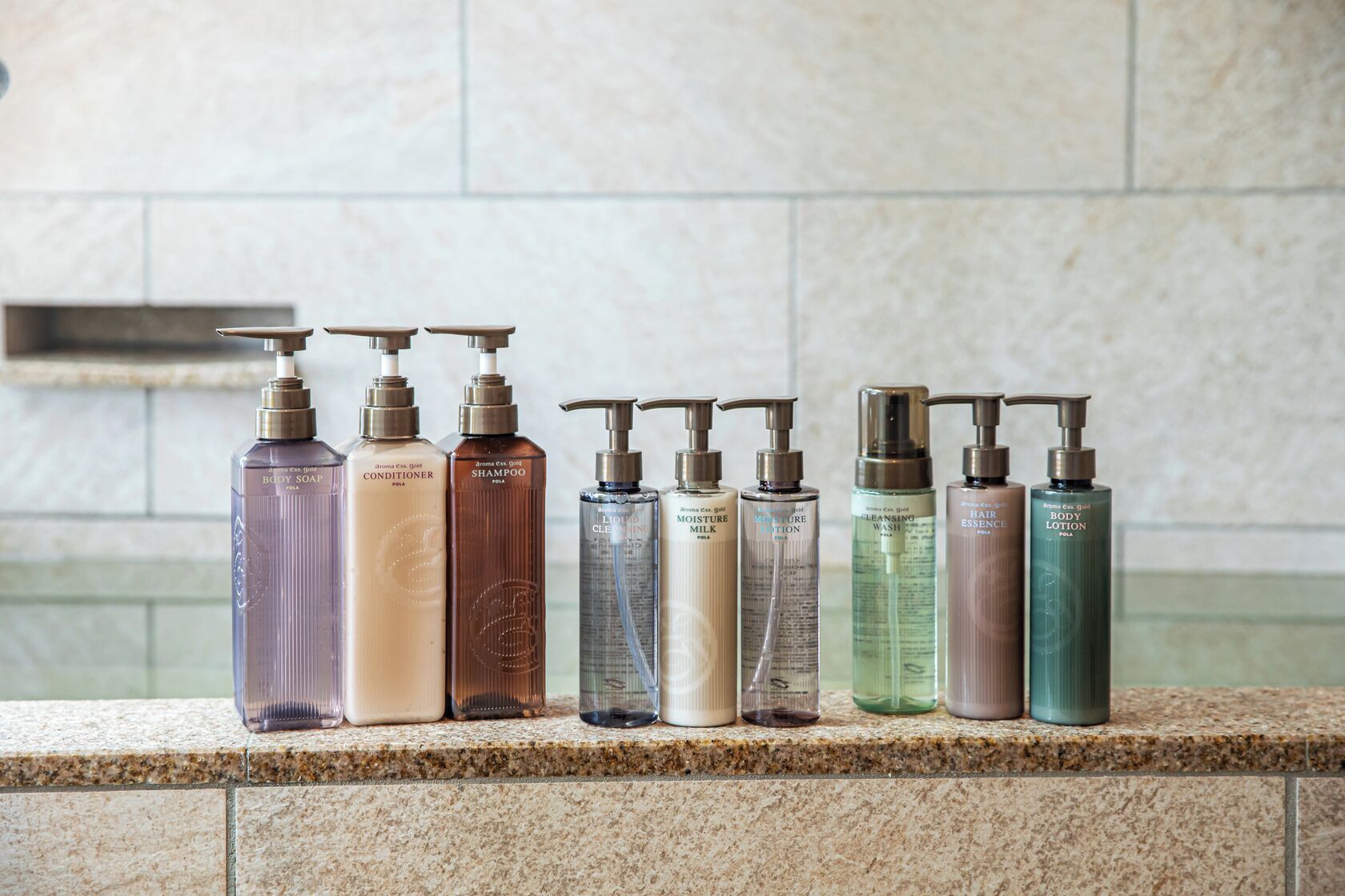 Une rangée de produits de toilette est disposée sur un comptoir en granit.