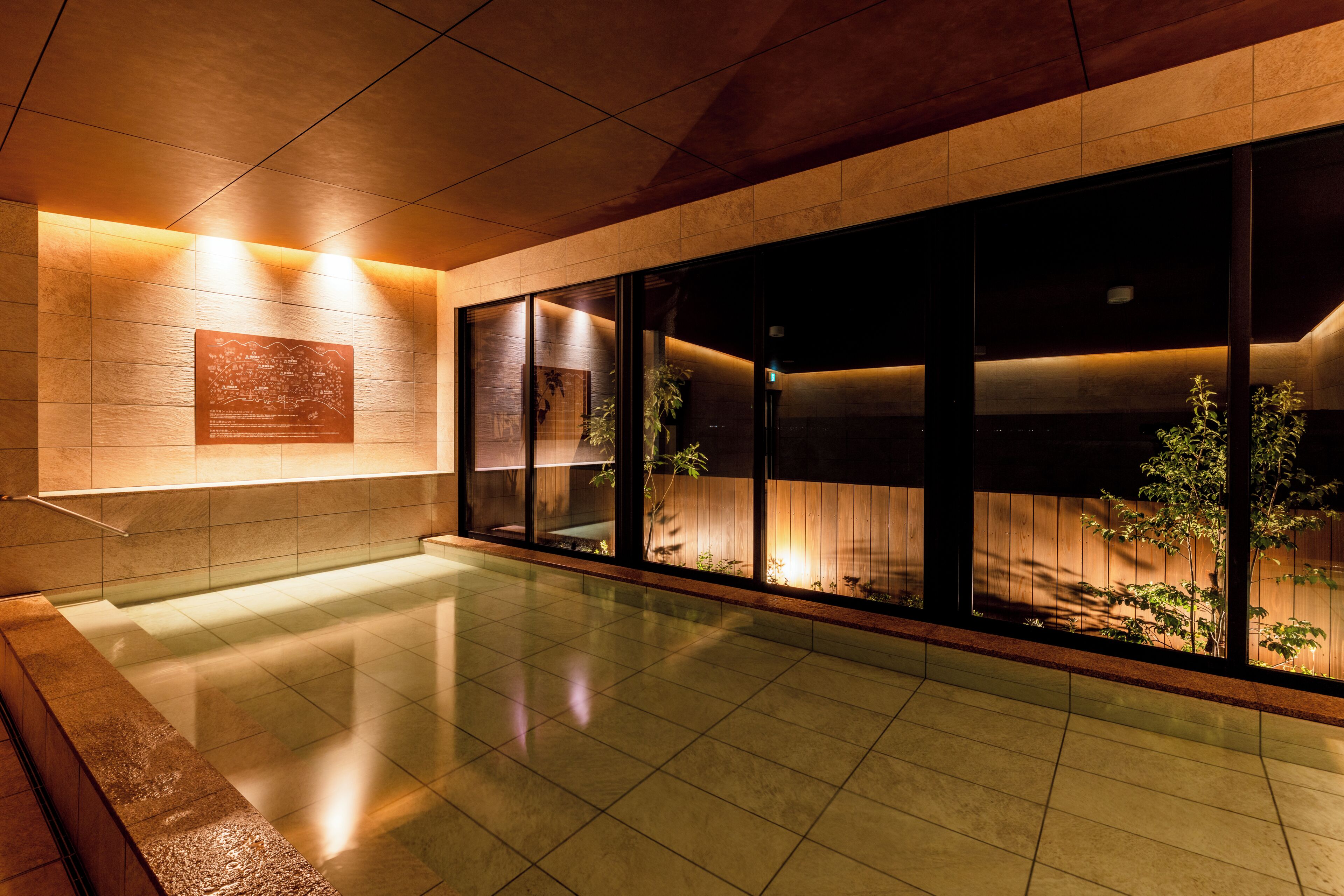 A modern interior with a reflective floor, a wooden bench, and a wall-mounted plaque.