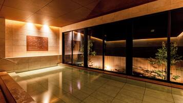 A modern interior with a reflective floor, a wooden bench, and a wall-mounted plaque.