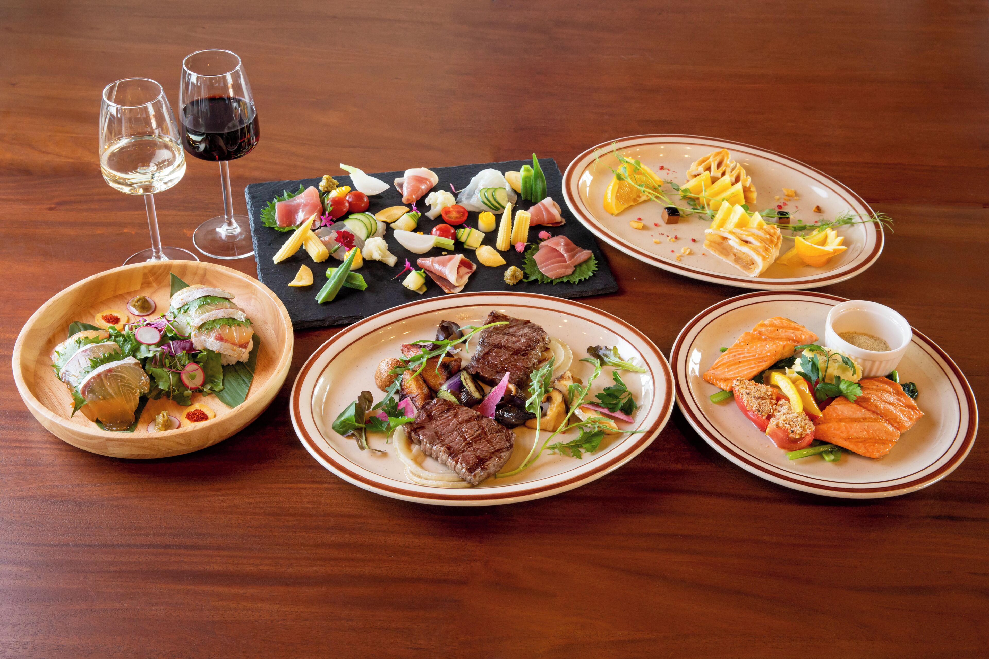 A table with various dishes and two glasses of wine.