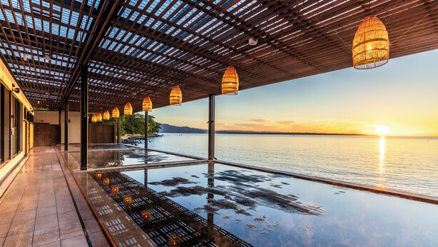 A glass infinity pool with a wooden pergola and hanging lamps, overlooking a calm body of water at sunset. - ISHINOYA Beppu (Beppu)