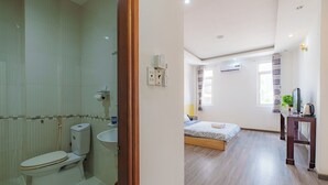 Un bagno con il water e un lavandino, una camera da letto con un letto e un comodino, e un pavimento in legno.