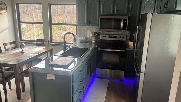 A compact kitchen with a central island, a microwave, an oven, and a refrigerator.