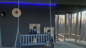 A wooden swing bench with a fire feature underneath, hanging from chains.