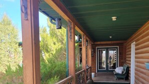 A covered porch with a view of the surrounding forest.