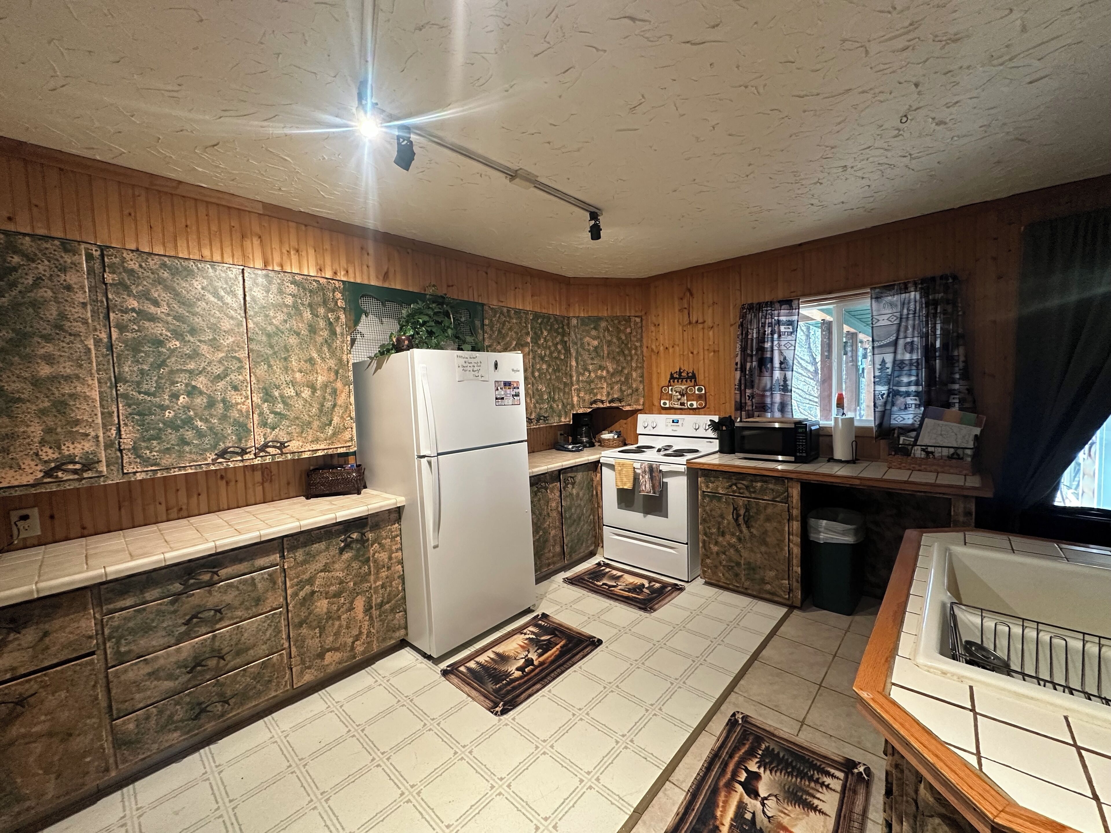 Une cuisine avec des meubles de rangement en bois, un réfrigérateur blanc, une cuisinière et un four à micro-ondes.