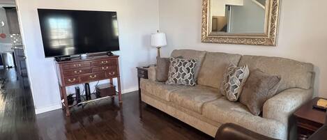 A living room with a flat-screen TV, a sofa, a coffee table, and a leather armchair.