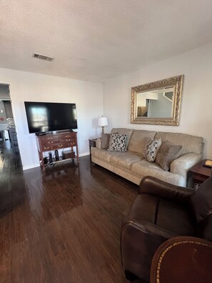 A living room with a flat-screen TV, a sofa, a coffee table, and a leather armchair. - Perfect Auburn Game Day Stay, Off S. College. Pet-friendly! (Auburn)