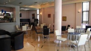 A spacious lobby with a bar area, multiple seating arrangements, and a large pillar. - New Heaven (Sarandë)