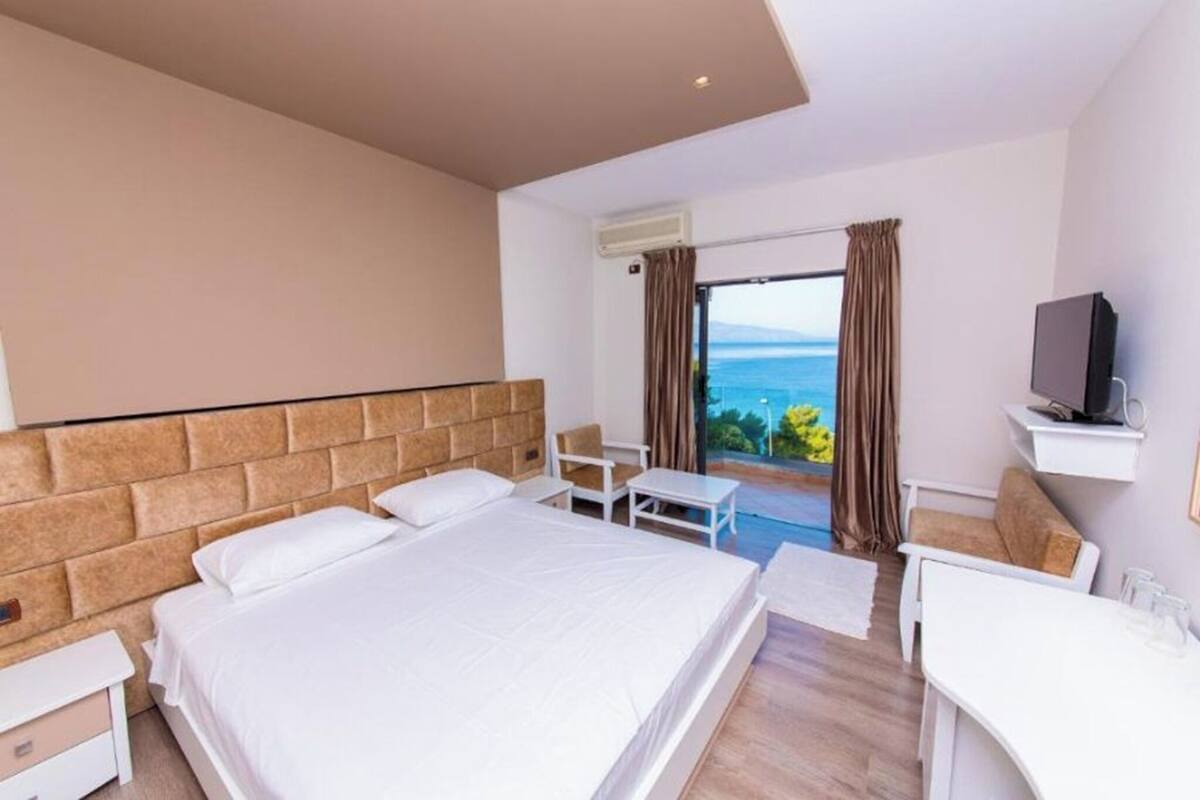 A hotel room with a large bed, a desk, a chair, and a TV.