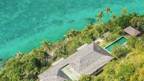 Un resort con piscina, exuberante vegetación y aguas turquesas cristalinas.