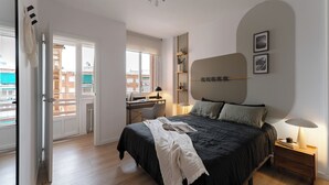 Un dormitorio moderno con una cama grande, un escritorio y vistas a la ciudad a través de la ventana.