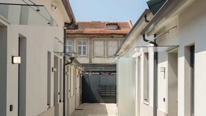 Um corredor estreito com piso de azulejos que leva à entrada de um edifício.