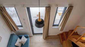 Uma sala de estar moderna com um sofá azul, um pendente e uma escada de madeira.