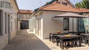 Pátio com área de estar ao ar livre, telhado telhado e entrada de um edifício.