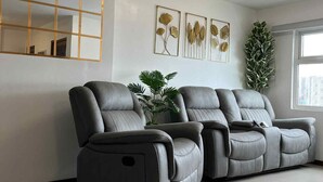 Una sala de estar moderna con un sofá seccional gris, un espejo grande y decoración en la pared.