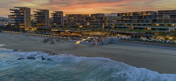 På stranden, hvit sand, strandtelt (mot et tillegg) og solsenger
