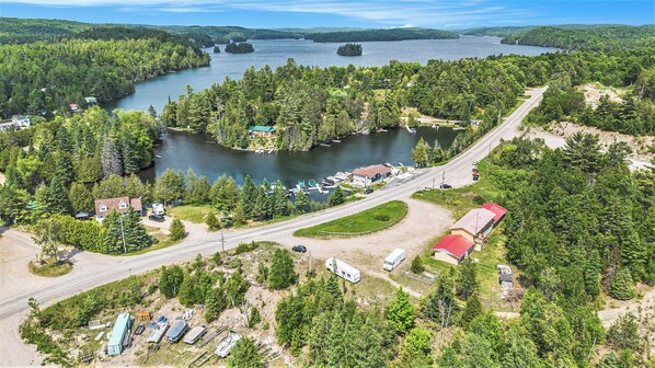 An aerial view of a lakeside property with a road, boats, and cabins. - PALMERSTON LAKE MOTEL (Ompah)