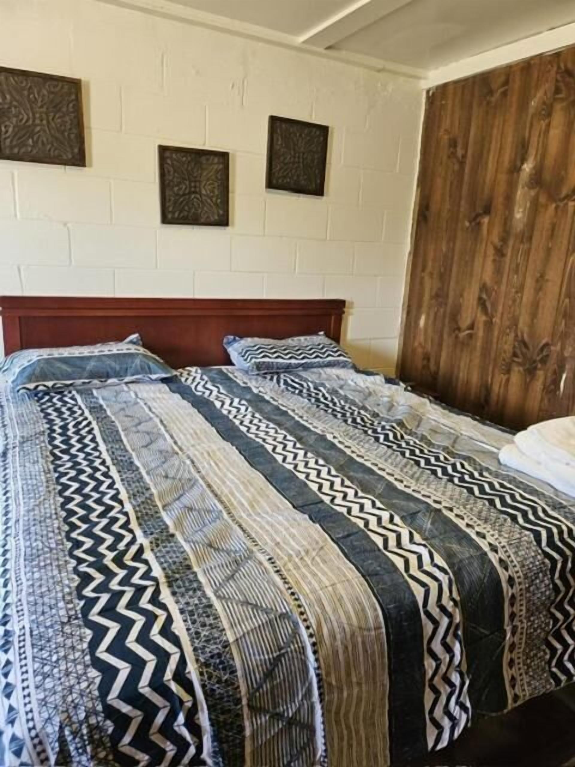 A bed with a patterned bedspread and a wooden headboard.