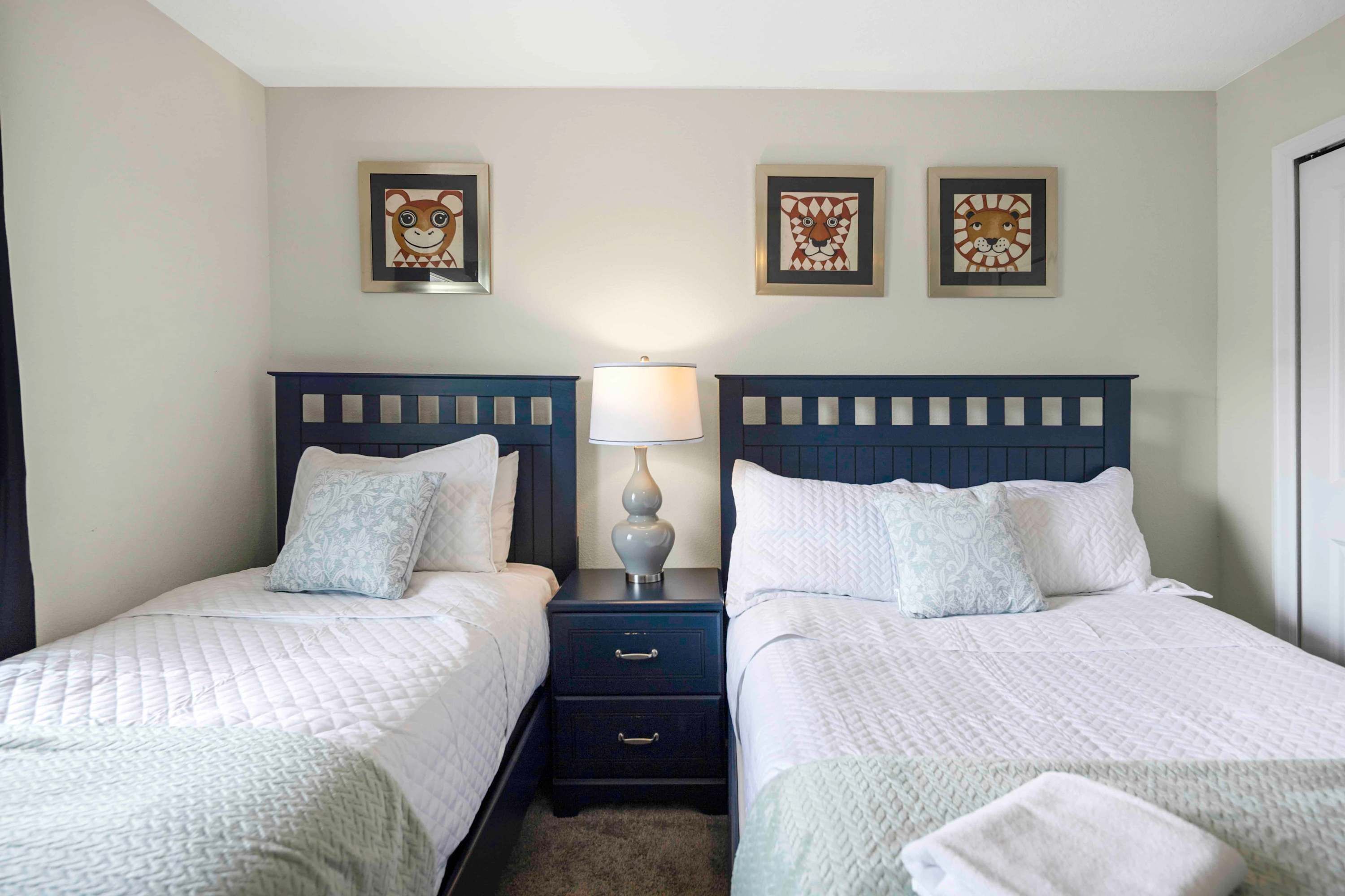 A twin room with two beds, a nightstand with a lamp, and decorative wall art.